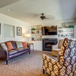 A cozy living room with a sofa, armchair, TV, and fireplace surrounded by decorative shelves.