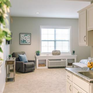 A cozy living room with a neutral color palette, featuring an armchair and large window.