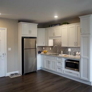 A modern kitchen with white cabinetry, stainless steel appliances, and wood flooring.
