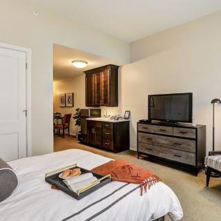 A modern bedroom with a stylish dresser, mounted television, and cozy decor.