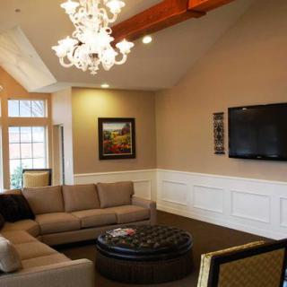 A cozy living room featuring a large sofa, chandelier, and mounted TV.
