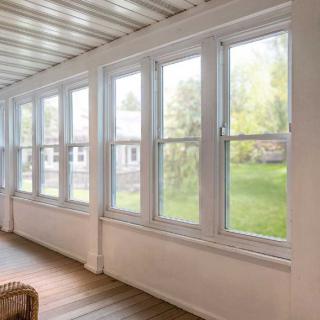 A bright sunroom with large windows offering a view of the outdoors.