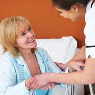 A nurse assisting and smiling at a patient in a healthcare setting.