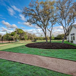 A picturesque view of a house surrounded by a well-maintained lawn, trees, and a clear blue sky.