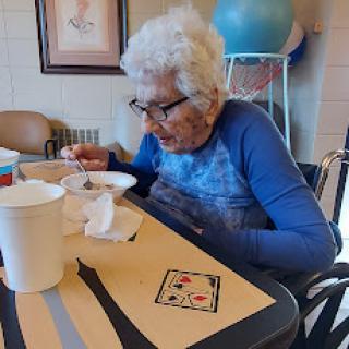 An elderly woman enjoying her meal in a cozy dining area.