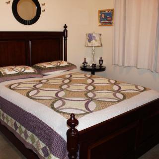 A cozy bedroom with a wooden bed frame, decorative quilt, and bedside lamp.