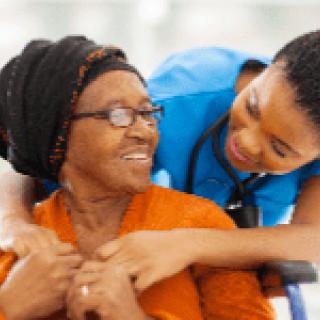 Nurse providing care and support to an elderly woman in a wheelchair.