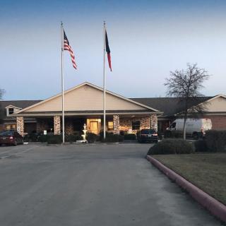 A building with flags in front and a parking lot at dusk.