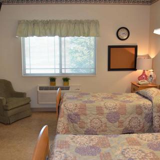 A cozy bedroom with twin beds and a comfortable chair by the window.