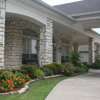 A beautifully landscaped house featuring stone exterior and vibrant flowers.