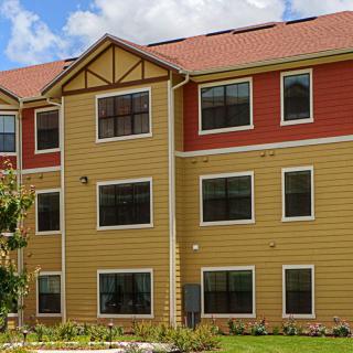 A three-story residential apartment building with multiple windows and a colorful exterior.