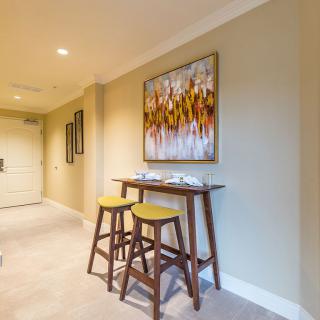 A modern hallway featuring a small table with two bar stools and vibrant artwork on the wall.