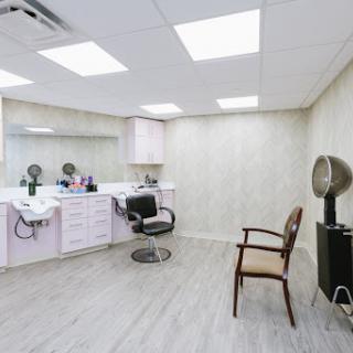 A well-lit hair salon interior featuring styling stations and chairs.