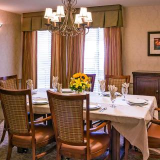 A cozy dining room with an elegantly set table and a chandelier overhead.