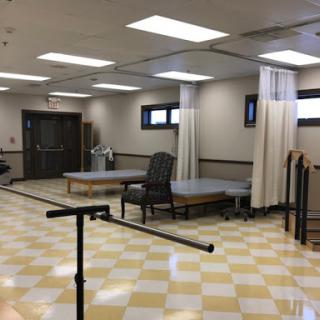 A spacious and well-lit physical therapy room equipped for rehabilitation exercises.