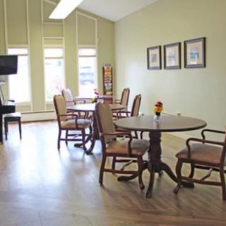 A bright and spacious dining area with wooden tables and chairs, adorned with wall art and large windows.