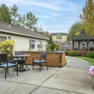 A cozy backyard patio with outdoor seating, a gazebo, and lush greenery.