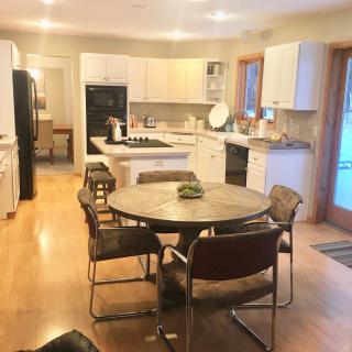 A modern kitchen with a dining table and chairs, featuring white cabinets and a central island.