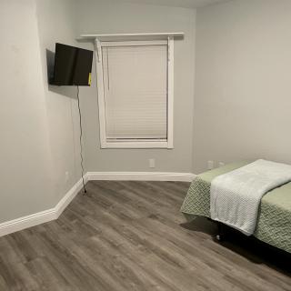 A minimalist bedroom with a single bed and wall-mounted TV.
