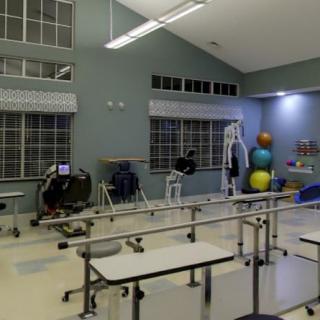 A rehabilitation room equipped with exercise machines, therapy balls, and parallel bars.