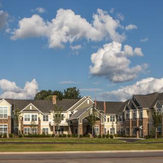 A picturesque suburban residential building under a partly cloudy sky.