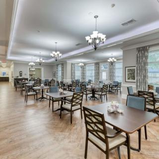 A spacious and elegantly decorated dining room with neatly arranged tables and chairs, featuring large windows and stylish lighting.