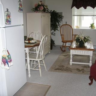 A cozy dining and kitchen area with a table, chairs, refrigerator, and decorative items.