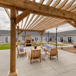 Outdoor patio area with a wooden pergola, cozy seating, and a fireplace.