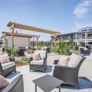 A modern outdoor patio area with comfortable seating and a wooden pergola in an apartment complex.