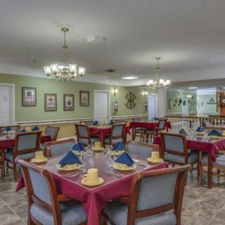 A well-organized dining room with neatly arranged tables and chairs, featuring chandeliers and elegant decor.