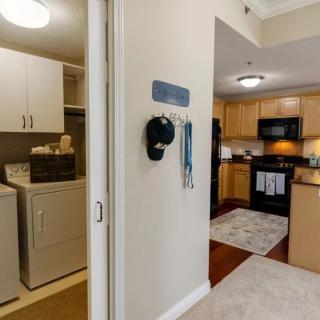 A view of a home's interior showcasing the laundry room with a washer and dryer, adjacent to a kitchen equipped with modern appliances.