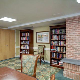 A cozy reading room with bookshelves, chairs, and a table.