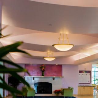 A well-lit lobby with chandeliers, featuring a fireplace and comfortable seating.