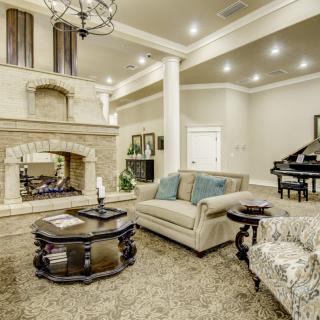 A luxurious living room with elegant furniture, a grand piano, and a large fireplace.