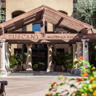 Entrance to the Tuscany-themed hotel with columns and lush greenery.