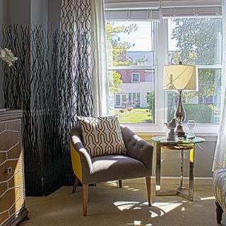 A cozy sitting area with a chair, side table, and lamp by the window.
