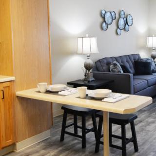 A modern living space featuring a small dining area with two stools and a cozy living room with a sofa.