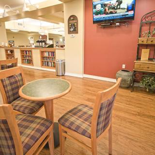 A cozy dining area with a table and chairs, featuring a wooden floor and a television mounted on the wall.