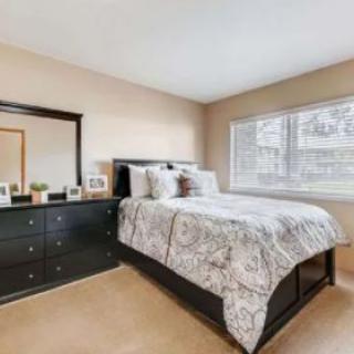 A cozy bedroom with a neatly made bed, dresser, and large window.