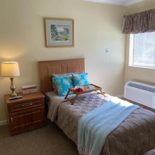 A cozy bedroom with a single bed, nightstand, and a window letting in natural light.