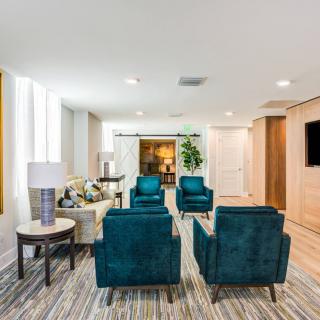 A modern living room with teal armchairs and contemporary decor.