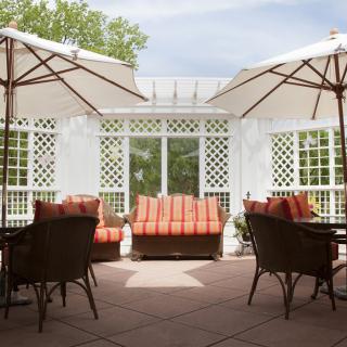 A cozy outdoor patio with wicker furniture and umbrellas on a sunny day.