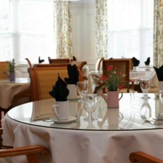 A well-arranged dining area with round tables, neatly set with black napkins and potted cactus plants.