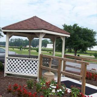 A charming gazebo surrounded by vibrant flowers, set against a tranquil landscape.