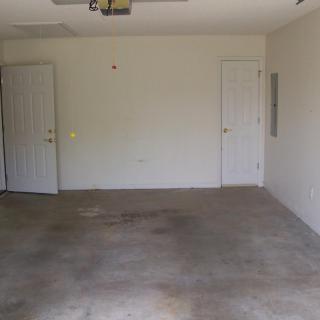 An empty garage with concrete flooring and two doors.