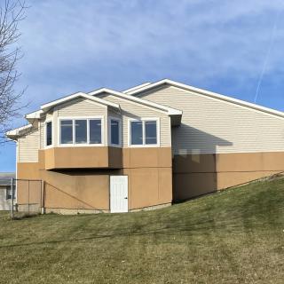 A residential house with a sloping lawn and a clear blue sky.