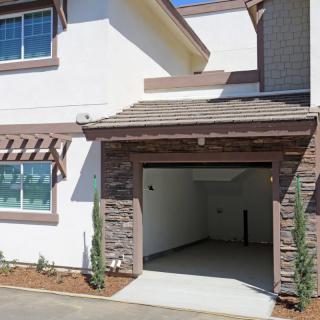 A modern house with an open garage and a small driveway.