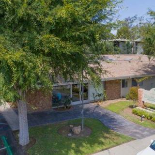 A suburban home surrounded by trees and a neatly maintained lawn.