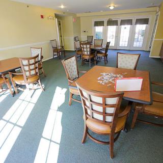 A well-lit dining area with neatly arranged tables and chairs, ideal for community gatherings.
