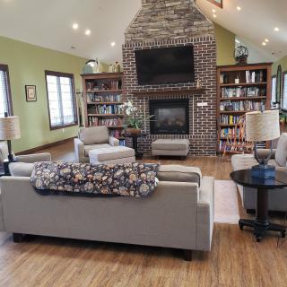 A cozy living room with a stone fireplace, flanked by bookshelves and comfortable seating.